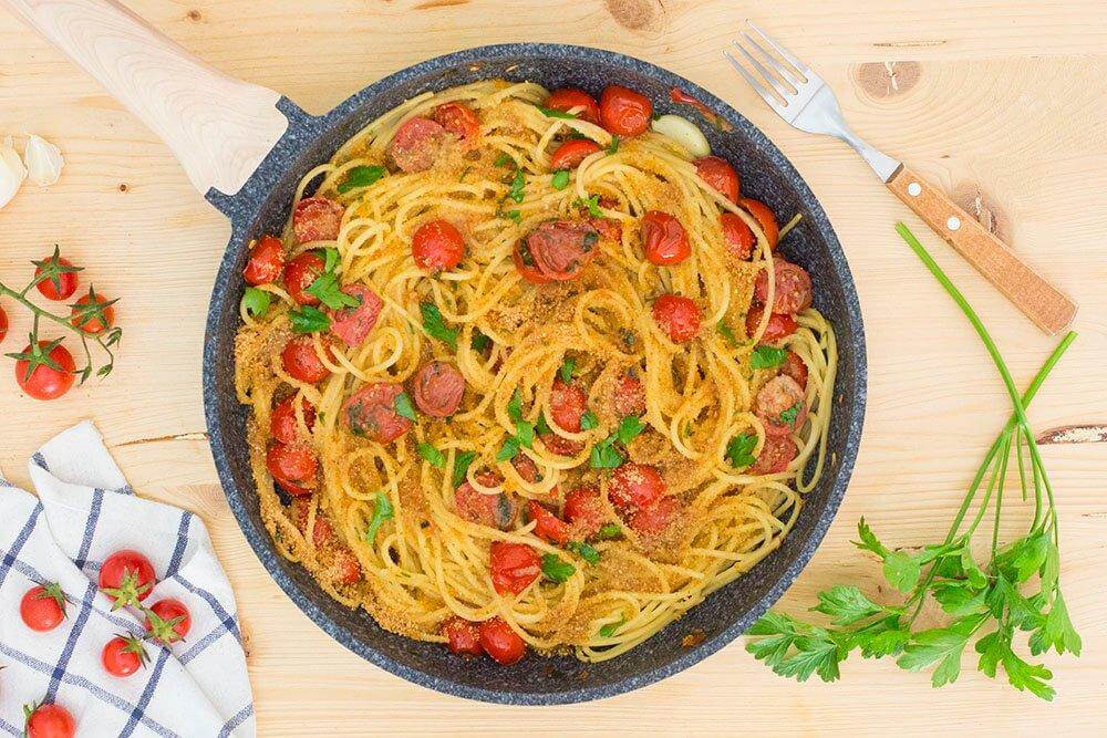 Delicious vermicelli pasta dish with cherry tomatoes and parsley in a skillet.