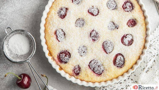 Delicious torta di ricotta topped with cherries and powdered sugar on a rustic table.
