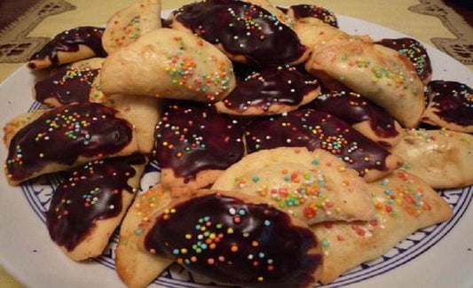 Delicious Calabrian Petrali cookies topped with chocolate and colorful sprinkles on a decorative plate.