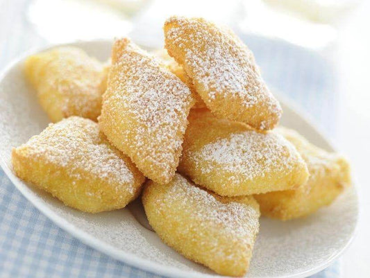 Delicious crema fritta pieces dusted with powdered sugar on a white plate.