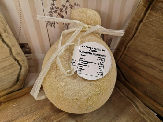 Caciocavallo di Ciminà cheese wheel with identification label and ribbon on rustic wooden background.