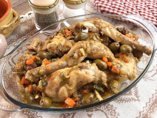 Delicious rabbit stew alla cacciatora with vegetables and olives served in a glass dish.