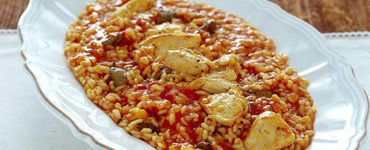 Delicious Risotto alla Sbirraglia served on a white platter, featuring chicken and tomato sauce.