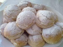 Delicious round pastries dusted with powdered sugar, arranged on a white plate.