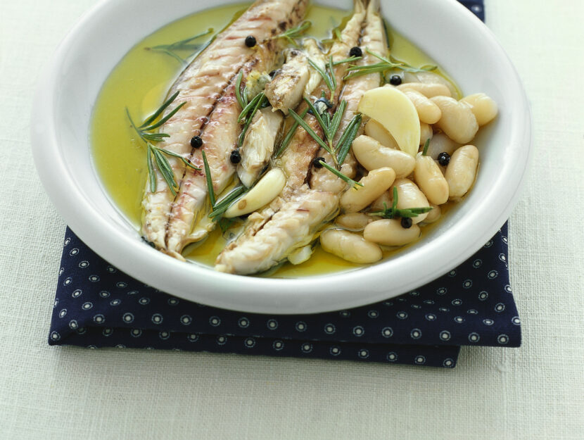 Filetti Sgombro al bergamotto su un letto di fagioli bianchi, con rosmarino e pepe in un piatto bianco.