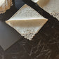 Set of vintage Burano lace napkins displayed on a dark marble table, showcasing intricate craftsmanship.