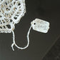 Close-up of intricate Burano lace with a tag reading 'FRL 248' on a dark surface.