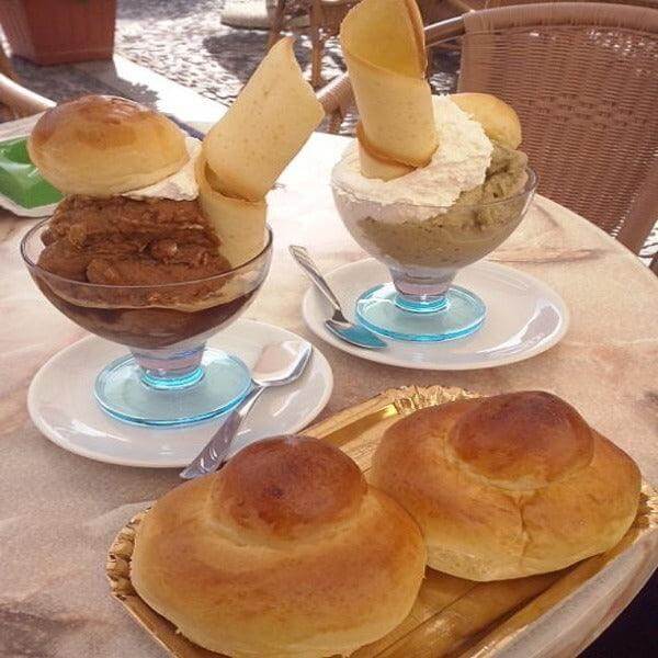 Brioche col Tuppo served with gelato in a dessert cup, showcasing traditional Sicilian and Calabrian delicacies.