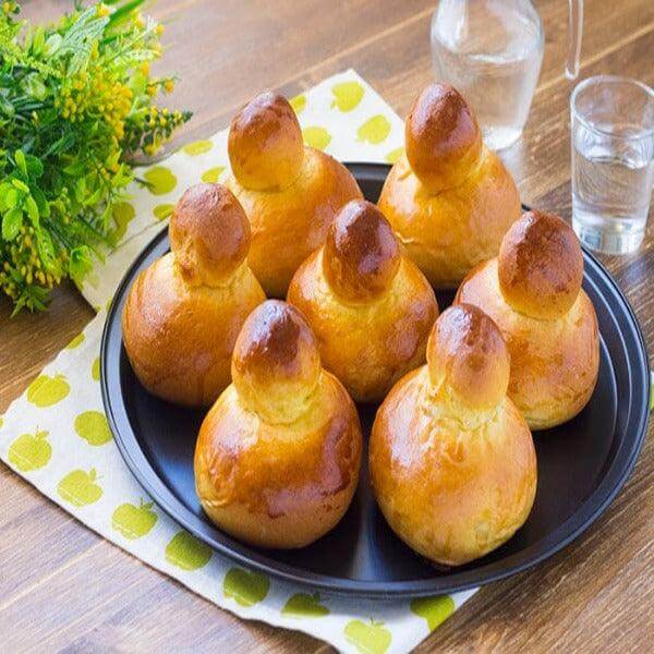 Freshly baked brioche col tuppo on a black plate, perfect for filling with gelato.