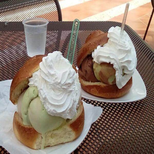 Delicious Sicilian brioche with ice cream and whipped cream served on a plate. Perfect summer treat.