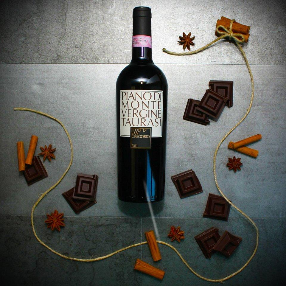 Taurarsi - Vino Rosso Campania DOCG bottle surrounded by chocolate and spices on a textured surface.