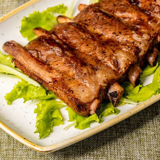Costine Ribs di Suino al Cirò Rosso DOCG su un letto di insalata verde, pronte da gustare.