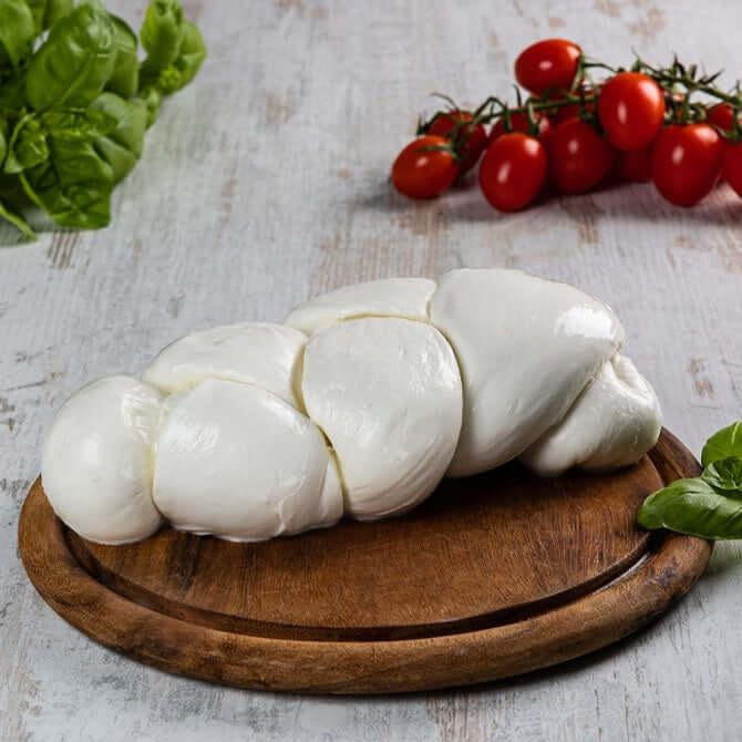 Mozzarella fior di latte 1 kg, handmade braided cheese on a wooden platter with cherry tomatoes and basil.