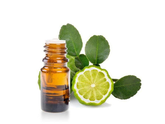 Essenza di Bergamotto in bottiglia con lime e foglie fresche di bergamotto.